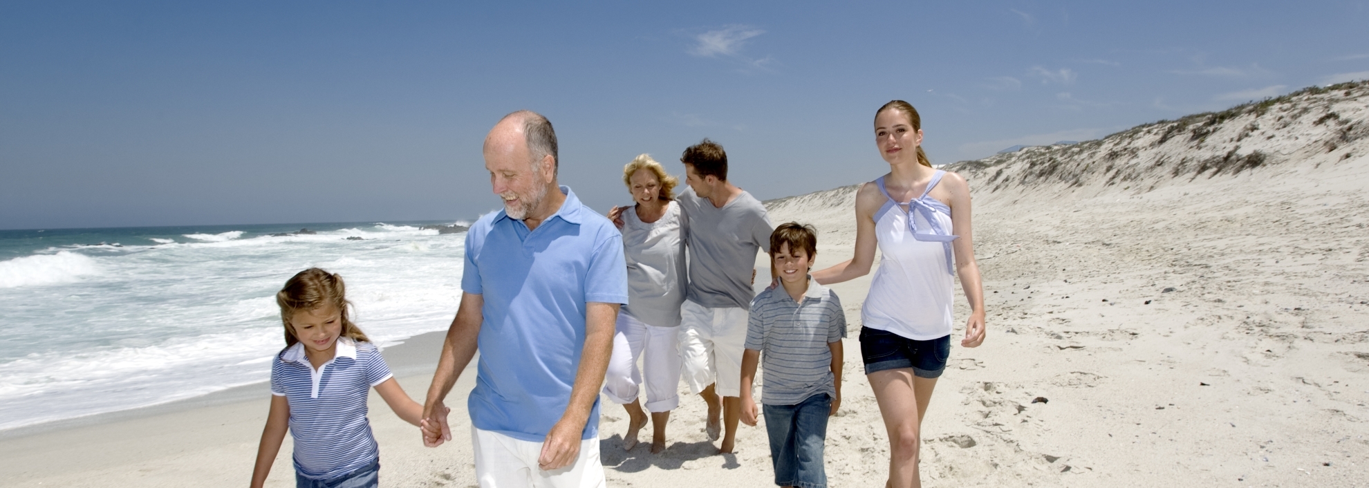 Three generations family walking on beach